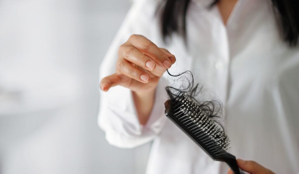 fibroid symptoms woman losing hair on hairbrush in hand