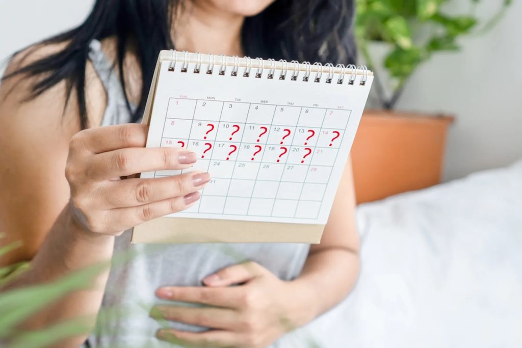 heavy periods woman hand holding calendar with question marks