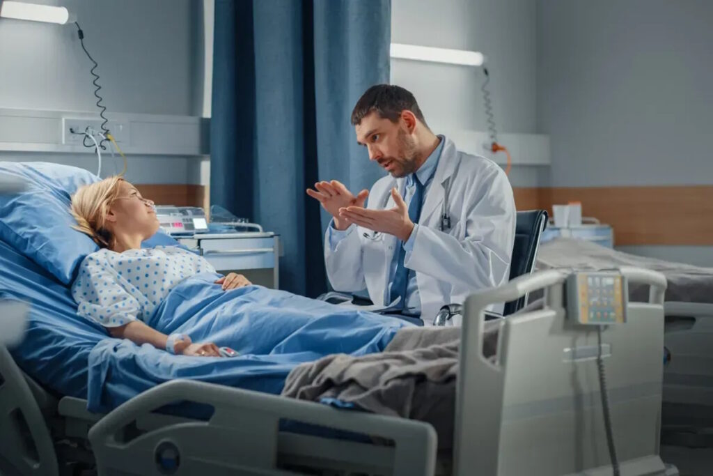 uterine fibroids fibroid treatment doctor talks to woman resting in hospital bed surgery prep ist321692342